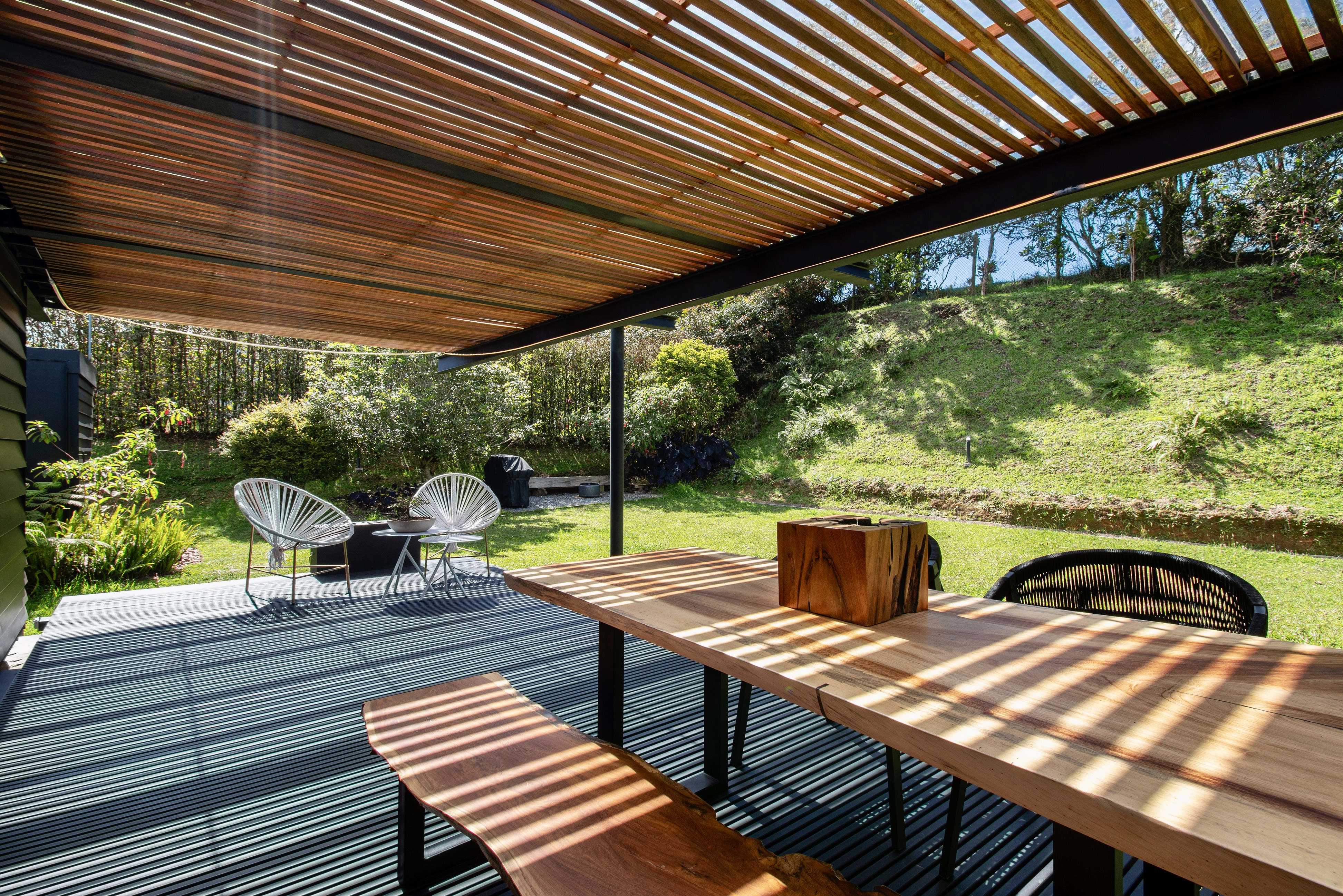 Covered timber deck with outdoor seating beside the garden