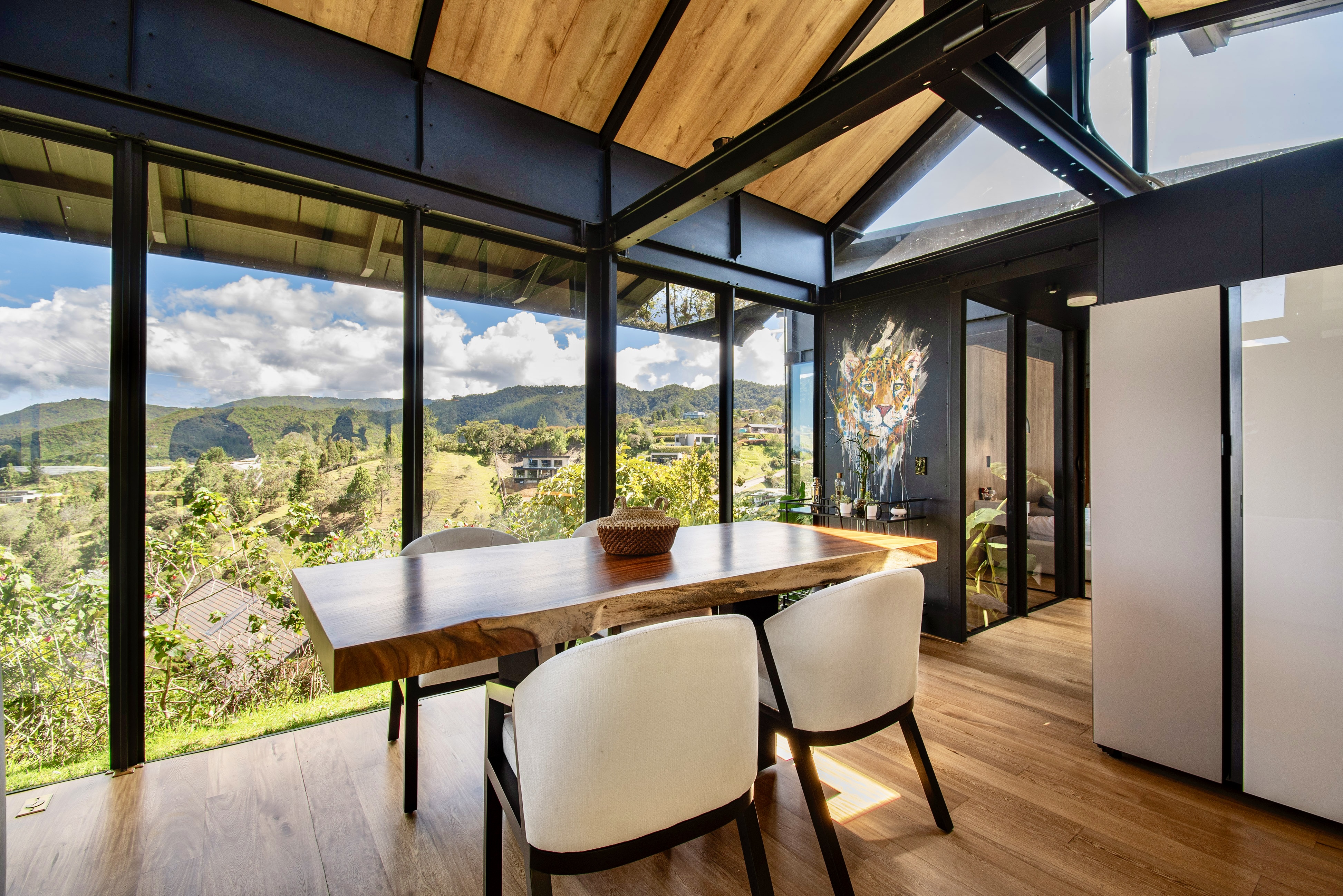 Dining table beside floor-to-ceiling windows overlooking the hills