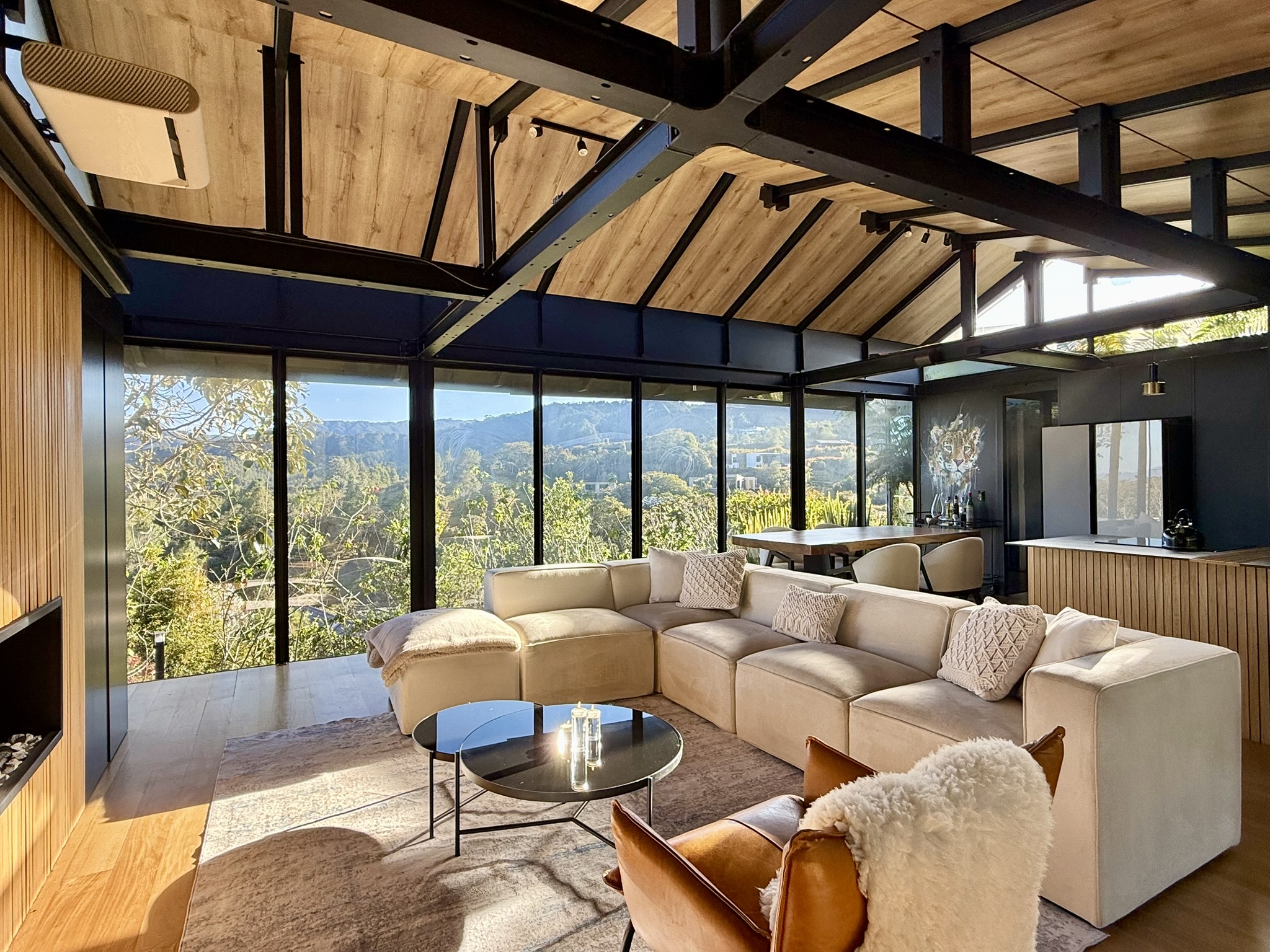 Living room with cream seating, exposed dark beams and garden glazing